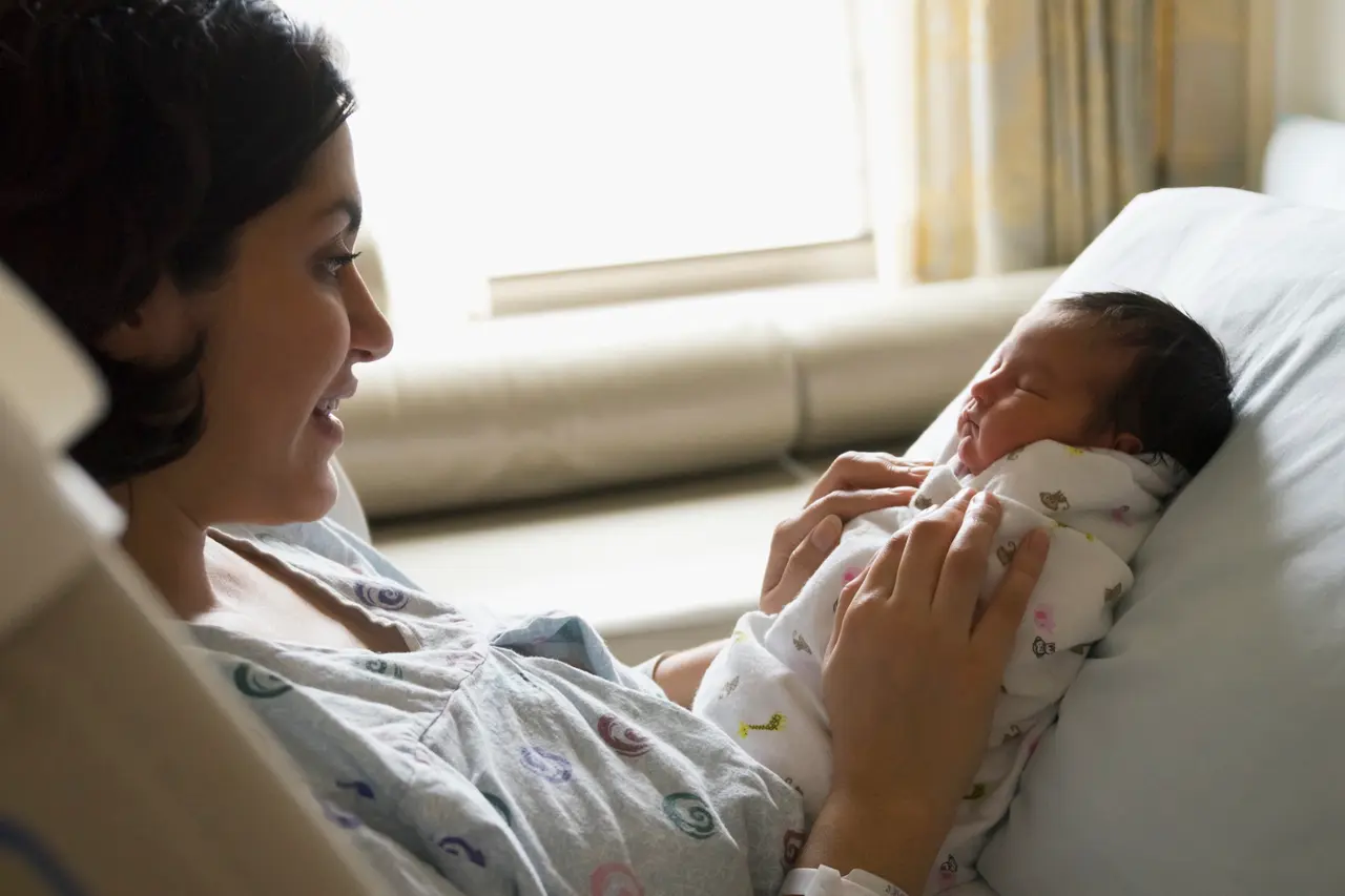 Newborn baby resting in parent's hands — perinatal mental health.